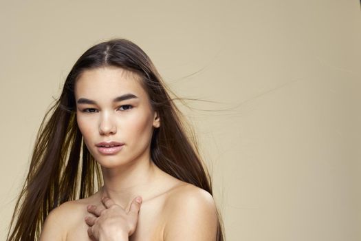 Pretty woman naked shoulders long hair body care beige background. High quality photo