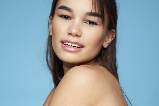 Woman with naked shoulders long hair cosmetics attractive look blue background. High quality photo