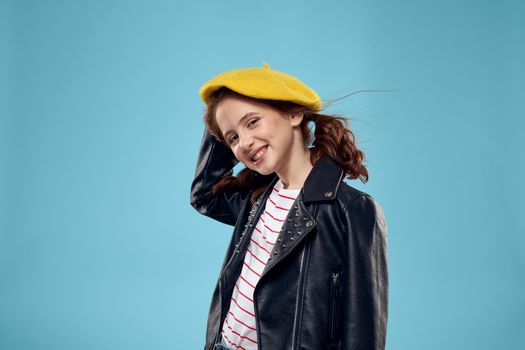 Fashionable girl in a black jacket with a yellow ticket striped T-shirt blue background. High quality photo