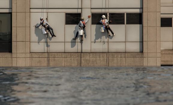 Group of workers cleaning windows service on high rise office building with reflection from swimming pool. Selective focus.