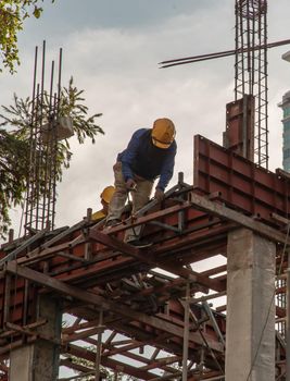 Construction Worker Welding soldering metal girders and Sparks in a Structure high above at the Construction site. Selective focus.