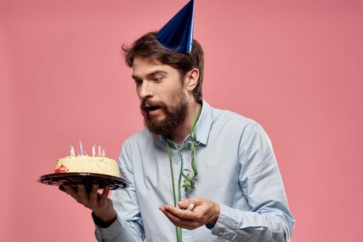 Bearded man with cake on pink background birthday party corporate emotions model loneliness. High quality photo