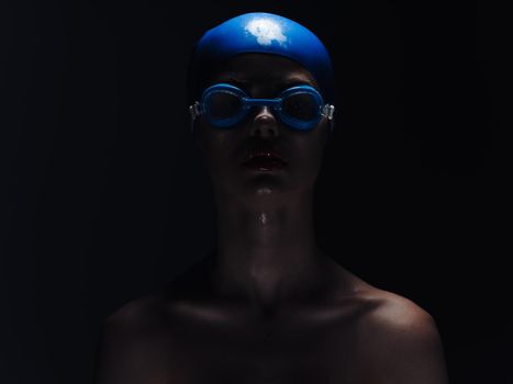 woman in a blue swimming cap and glasses on a black background. High quality photo