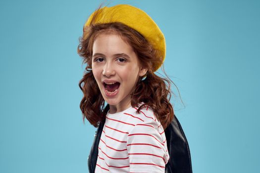 Fashionable girl in a black jacket with a yellow ticket striped T-shirt blue background. High quality photo