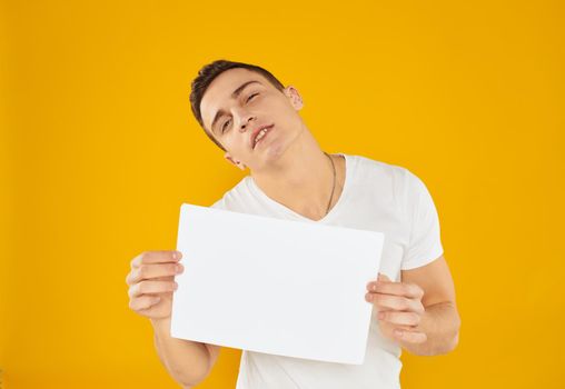 Guy with white sheet of paper mockup yellow background Copy Space. High quality photo