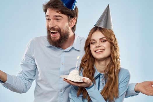 Cheerful man and woman with cake in a plate corporate party blue background. High quality photo