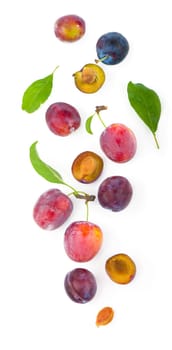Ripe plums with leaves close up on white background.