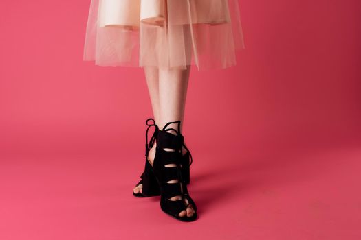 Female feet black fashionable heels shoes charm pink background. High quality photo