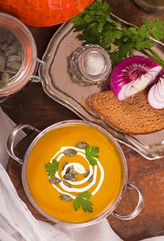 Bowl of pumpkin soup on rustic wooden background.