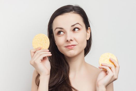 brunette with flowing hair naked shoulders sponge near face. High quality photo