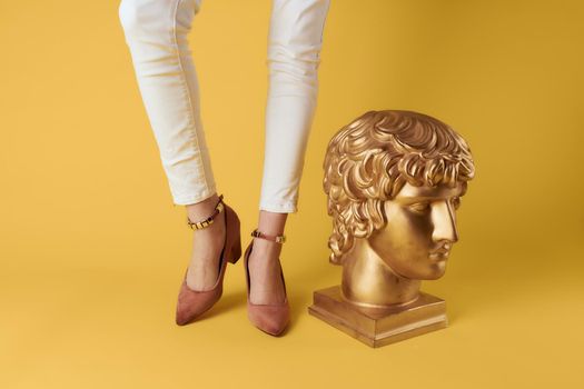Female feet head sculptures golden color luxury fashion yellow background. High quality photo