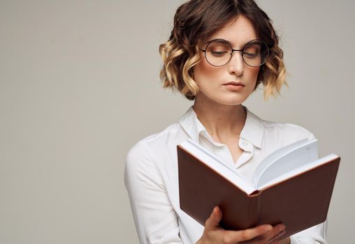 Smart woman with a notebook in her hands and in a white shirt on a gray background cropped view. High quality photo