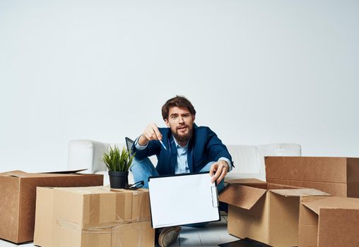 Business man sitting on the floor with boxes unpacking documents to the office manager. High quality photo