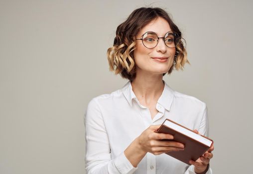 Business woman in a white shirt holds a notepad in her hand on a gray background. High quality photo