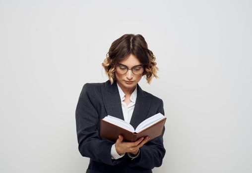 A woman in a suit with a notebook in her hands on a light background work model. High quality photo