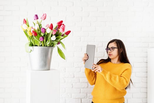Blogging. Woman blogger holding digital tablet taking picture of tulips flowers