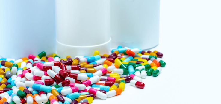 Pile of colorful antibiotic capsule pills on blurred plastic drug bottles. Antibiotic drug resistance concept. Antibiotic drugs smart use. Drug interactions. Pharmaceutical industry. Polypharmacy.