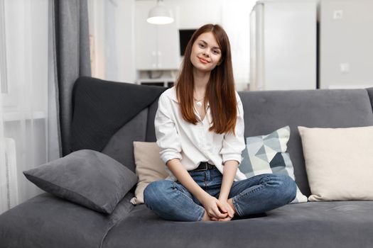 woman sitting on the couch bending her knees at home in an apartment rest. High quality photo