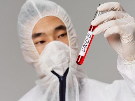 Male laboratory assistant Asian appearance blood tests for covid-19 close-up. High quality photo