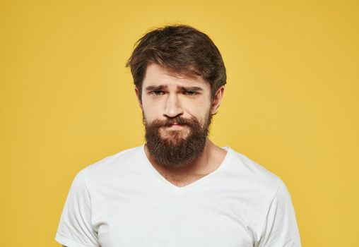 Emotional man on a yellow background in a white t-shirt thick beard brunette model. High quality photo