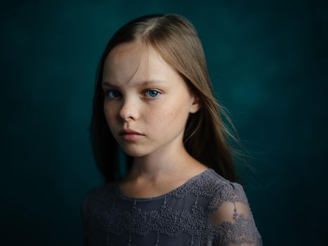 Portrait of a blue-eyed girl in a gray dress on a green background close-up beautiful face. High quality photo