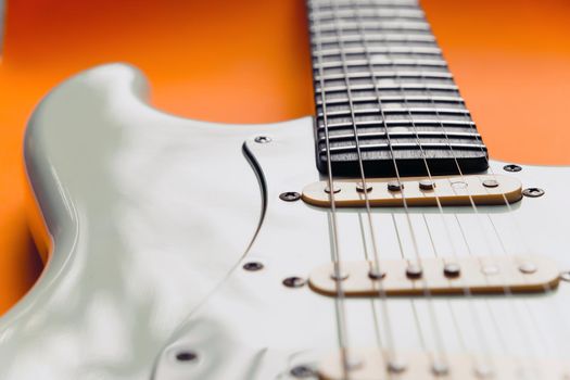 Detail of White Electric Guitar on a orange background.
