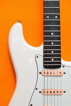 Detail of White Electric Guitar on a orange background.