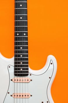 Detail of White Electric Guitar on a orange background.