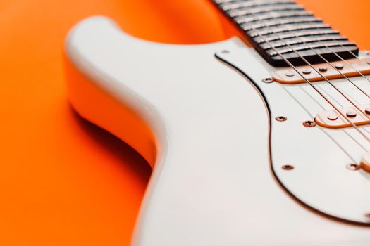 Detail of White Electric Guitar on a orange background.
