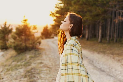 Traveler with a blanket on her shoulder stands on the road near the trees forest fresh air. High quality photo