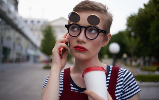 a woman in a sundress walks down the street with a cup of coffee in her hand. High quality photo