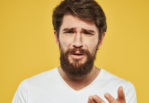 A brunette man with a thick beard on a yellow background emotions model. High quality photo