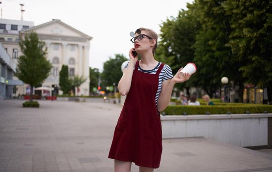 fashionable woman in a sundress and glasses on her face street nature summer trees building. High quality photo