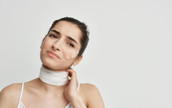 brunette with a bandaged neck holding her head health problems. High quality photo