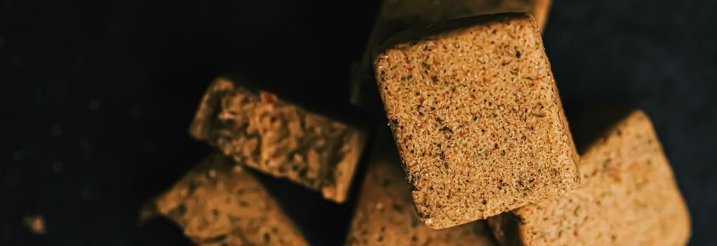 Vegetable bouillon cubes on stone kitchen board, stock or broth ingredient for soup, closeup