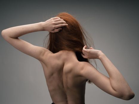 nude woman gesturing with her hands red hair light background. High quality photo