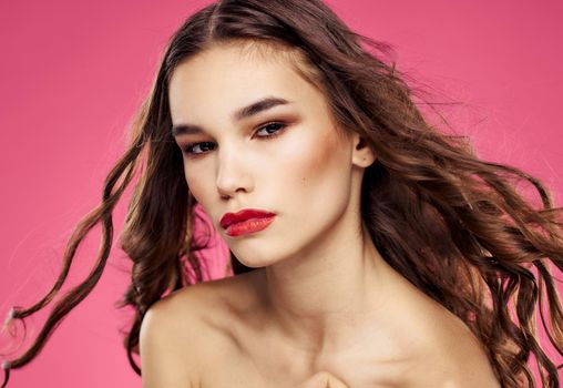 Red lips beautiful brunette curly hair pink background. High quality photo
