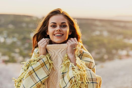 Romantic woman in a warm sweater with a plaid on her shoulders on nature in the mountains. High quality photo