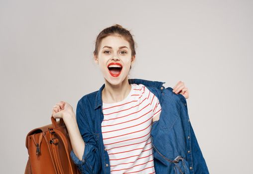 Cheerful pretty female student with backpack fashionable clothes training gray background. High quality photo