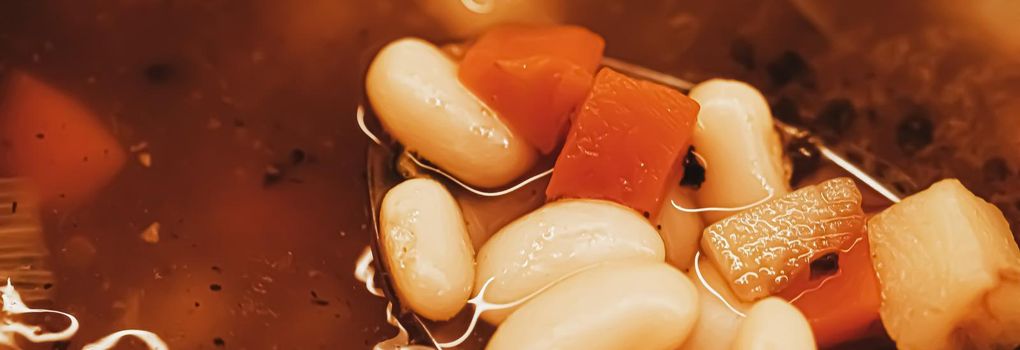 Vegetable soup with beans boiling in a saucepan, homemade food closeup