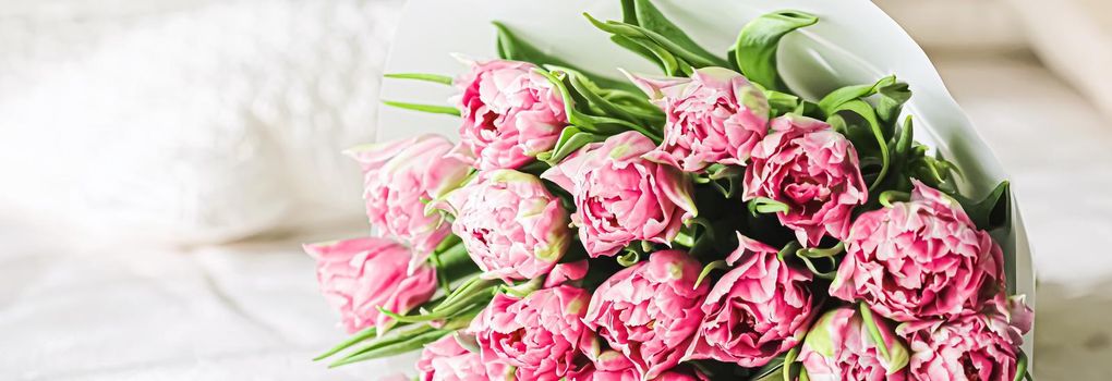 Romantic bouquet of pink tulips on bed in bedroom, holiday gift concept