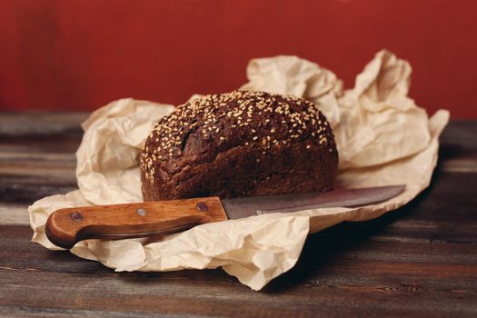 rye bread baking on paper packaging wooden table and sharp knife. High quality photo
