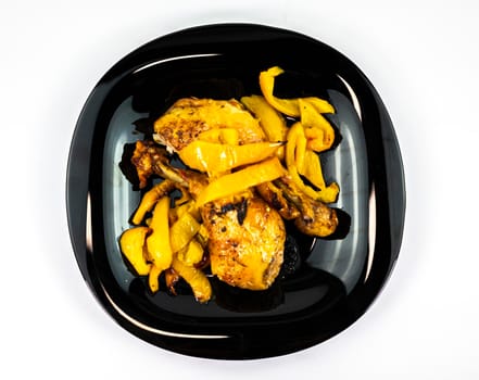 chicken so with yellow peppers on a black plate white background