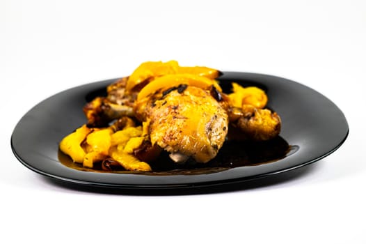 chicken so with yellow peppers on a black plate white background