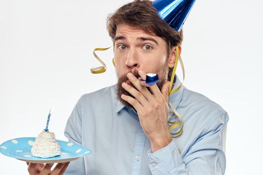 A man with a cake plate and in a blue shirt on a light background birthday party corporate cap. High quality photo
