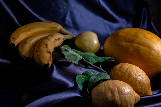 yellow fruit on a black background with melon bananas apples and lemons