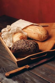 flour products rye bread on a tray and a sharp knife on a table on a red background. High quality photo