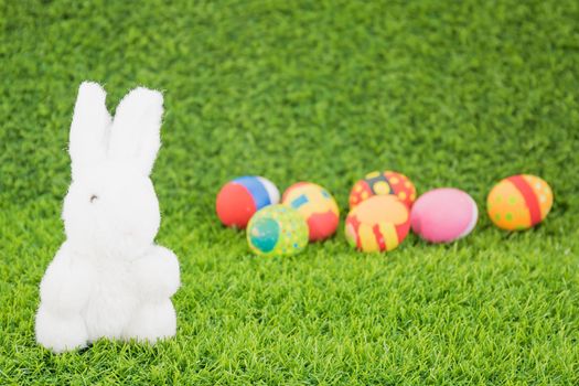 Easter bunny toy and Easter eggs on green grass