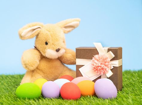 Colorful Easter eggs and gift box on grass  with blue background