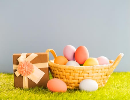 Colorful easter eggs in the basket on green grass background with copy space